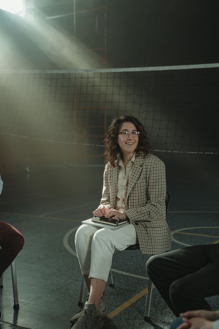A supportive group therapy session in a gymnasium with natural light and relaxed atmosphere.
