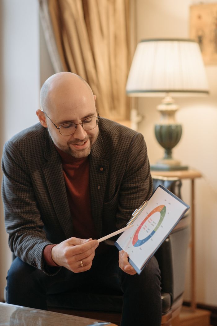 The Art of Drawing Readers In: Your attractive post title goes here Adult man explaining a color-coded diagram on a clipboard in a cozy room setting.